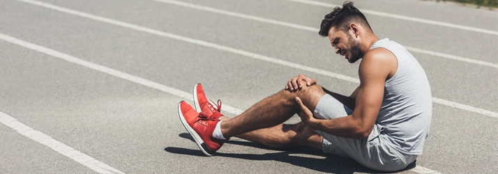 Chiropractic Naperville IL Knee Pain Track Runner Injury Man holding his knee in pain.